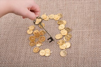Hand holding a retro styled key over fake gold coins
