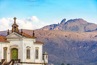 Antique baroque church in the city of Ouro Preto in Minas Gerais with the mountains and peak of Itacolomi in the background during sunset