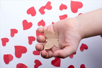 Paper butterfly and red paper hearts in hand