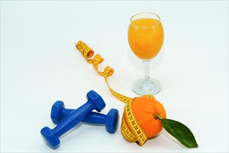 Orange with leaves surrounded by a tape measure with dumbbells and a glass of fresh orange juice
