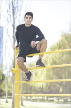 Young man posing after doing climbing vertical exercise in the park