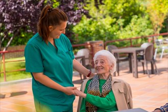 An older or mature woman with the nurse in the garden of a nursing home or retirement home