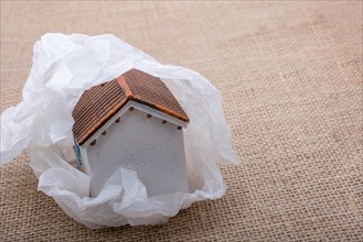 Little model house wrapped in paper on a brown background