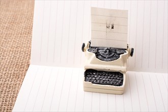 Retro syled tiny typewriter model on a paper background