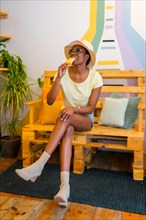 Portrait of black African ethnicity woman eating a mango ice cream in a shop