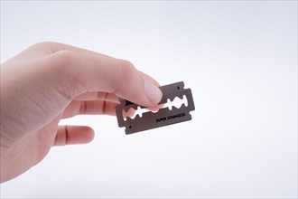 Hand holding a razor blade on a white background
