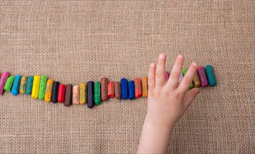 Toddlers hand putting crayons in line on canvas