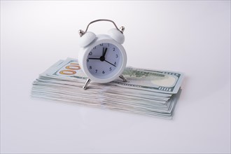 American dollar banknotes by the side of a alarm clock on white background