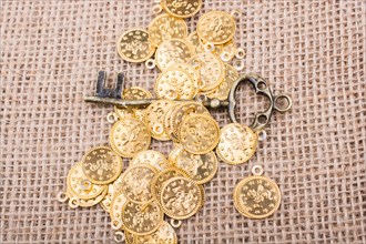 Retro styled key placed over fake gold coins