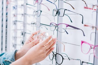 Female customer choosing glasses in an optical store. Girl hands choosing glasses in a store