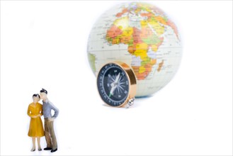 A couple by the side of a globe with a compass on isolated white background