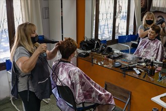 Latin hairdresser. Hairdresser blow-dries his client's hair. General shot