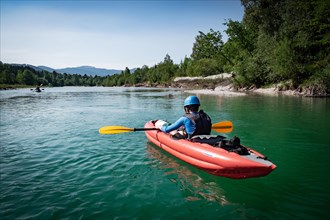 A boy paddles his kayak on a river in Upper Bavaria