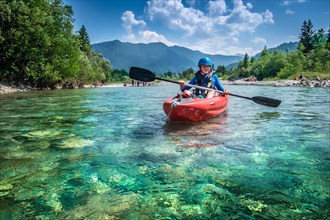 A child paddles his kayak on a river in Upper Bavaria
