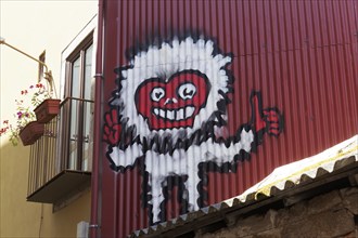 Scary figure with red face on red corrugated iron wall
