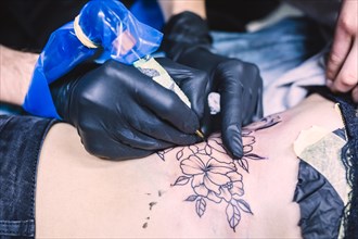 Hands making tattoo with machine