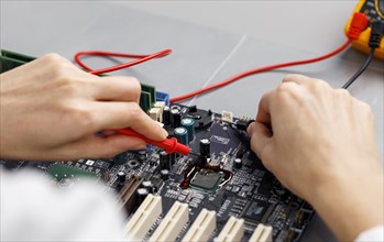 High angle female technician repairing computer motherboard