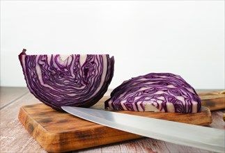 Sliced red cabbage on a wooden board with a knife in the foreground
