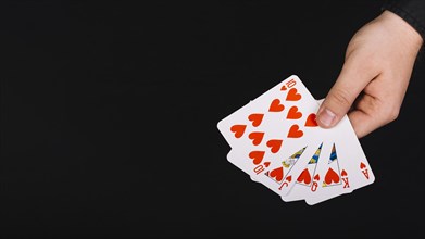 Poker player s hand royal flush heart black background