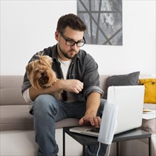Portrait adult male holding dog while working from home