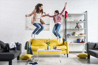Mother daughter jumping living room