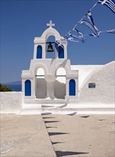 White bell tower with Greek flags
