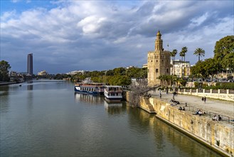 On the banks of the Guadalquivir river with the historic Torre del Oro tower in Seville
