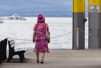 Tourist in colourful clothes on the jetty at Lake Constance
