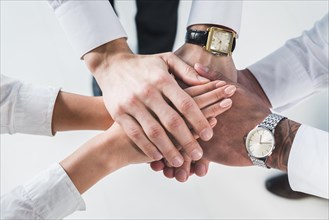 People putting stacked hands together promising help support against white backdrop