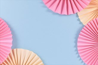 Beige and pink paper craft rosettes in corners of blue background with empty copy space in middle