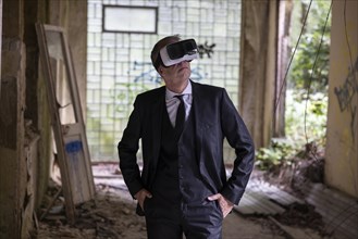 Man dressed in suit wearing VR glasses in a dilapidated office building