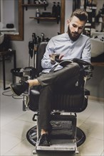 Customer watching magazine barbershop