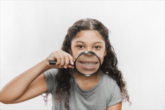 Close up girl with magnifying glass showing her teeth