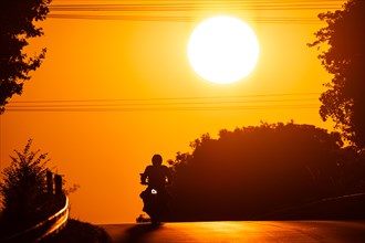 A motorbike rides along a country road near Frankfurt am Main at sunrise