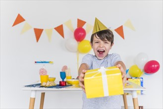 Cheerful boy taking yellow gift box with white ribbon