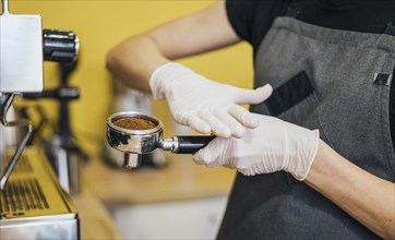 Side view barista with latex gloves preparing coffee machine
