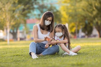 Asian mother daughter using disinfectant outside
