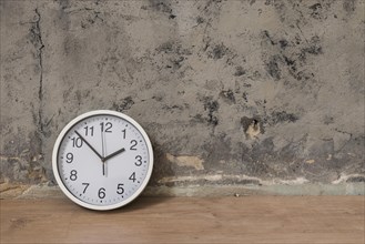 Clock wooden desk against weathered wall