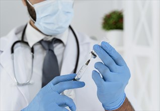 Blurred doctor with medical mask holding syringe