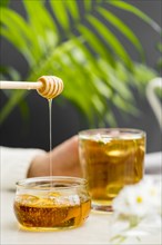 Front view woman holding glass with tea honey dipper