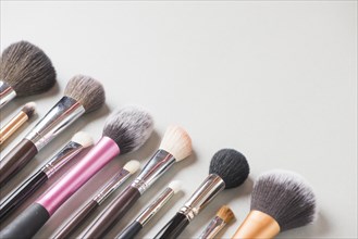 Various makeup brushes arranged row white backdrop