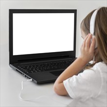 Little girl using laptop with headphones