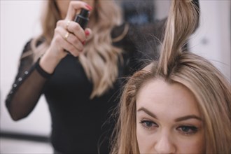 Crop hairdresser applying spray hair