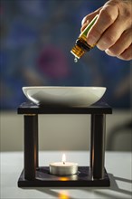 One person drips essential fragrance oil into a bowl
