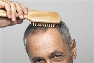 Close up senior man brushing hair