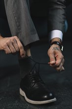 Low section businessman s hand tying shoelace