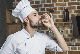 Professional male chef showing sign delicious