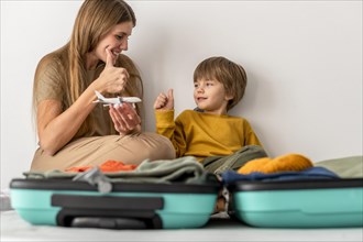 Mother child with luggage home giving thumbs up