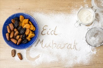 Eid mubarak inscription flour near dried fruits