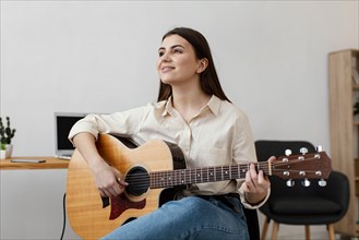 Front view smiley female musician playing acoustic guitar